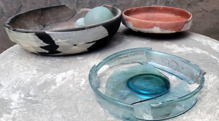 Pompei -  tavolino circolare a tre piedi con sopra ancora una coppa in ceramica contenente due ampolline in vetro, un piattino in sigillata ed un altro piattino in vetro.