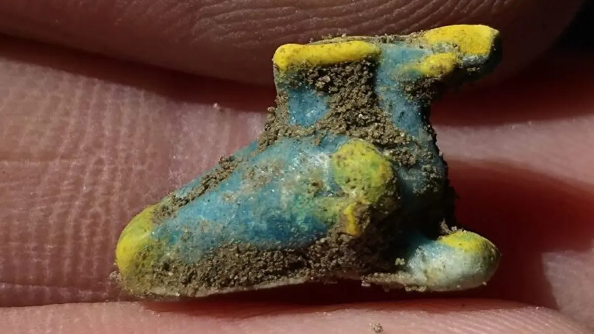 Piccolo pendente a forma di calzare alato, con tracce di terreno, rinvenuto durante lo scavo di un armadio nella Regio IX di Pompei.